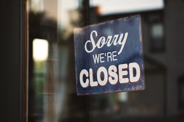 Granatowa tabliczka z napisem: sorry we're closed wisi na szklanych drzwiach.