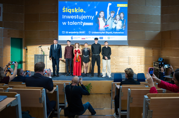 Członek Zarządu Województwa Śląskiego - Pan Rafał Adamczyk stoi na scenie w towarzystwie 5 wyróżnionych stypendystów projektu